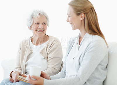 Buy stock photo Bonding, senior mother and women with tea in home, smile and connection together on weekend. Elderly parent, adult daughter and love in living room with drink, book and gossip with happy family