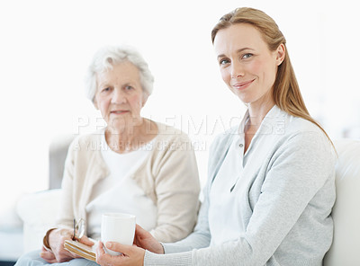 Buy stock photo Love, senior mother and women with coffee in home, smile and connection together on weekend. Elderly parent, adult daughter and bonding in living room with drink, book and portrait of happy family