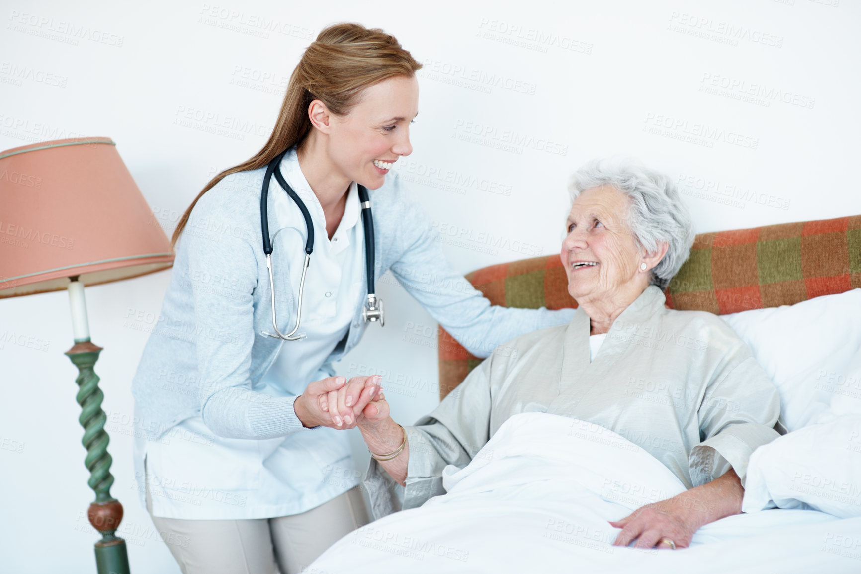 Buy stock photo Caregiver, support and senior woman in bed for homecare, healthcare and holding hands with smile. Help, happy and medical service with nurse and elderly patient in retirement at  nursing home