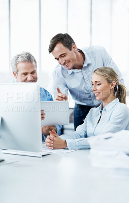 Buy stock photo Three businesspeople looking at a digital tablet while working together in their office