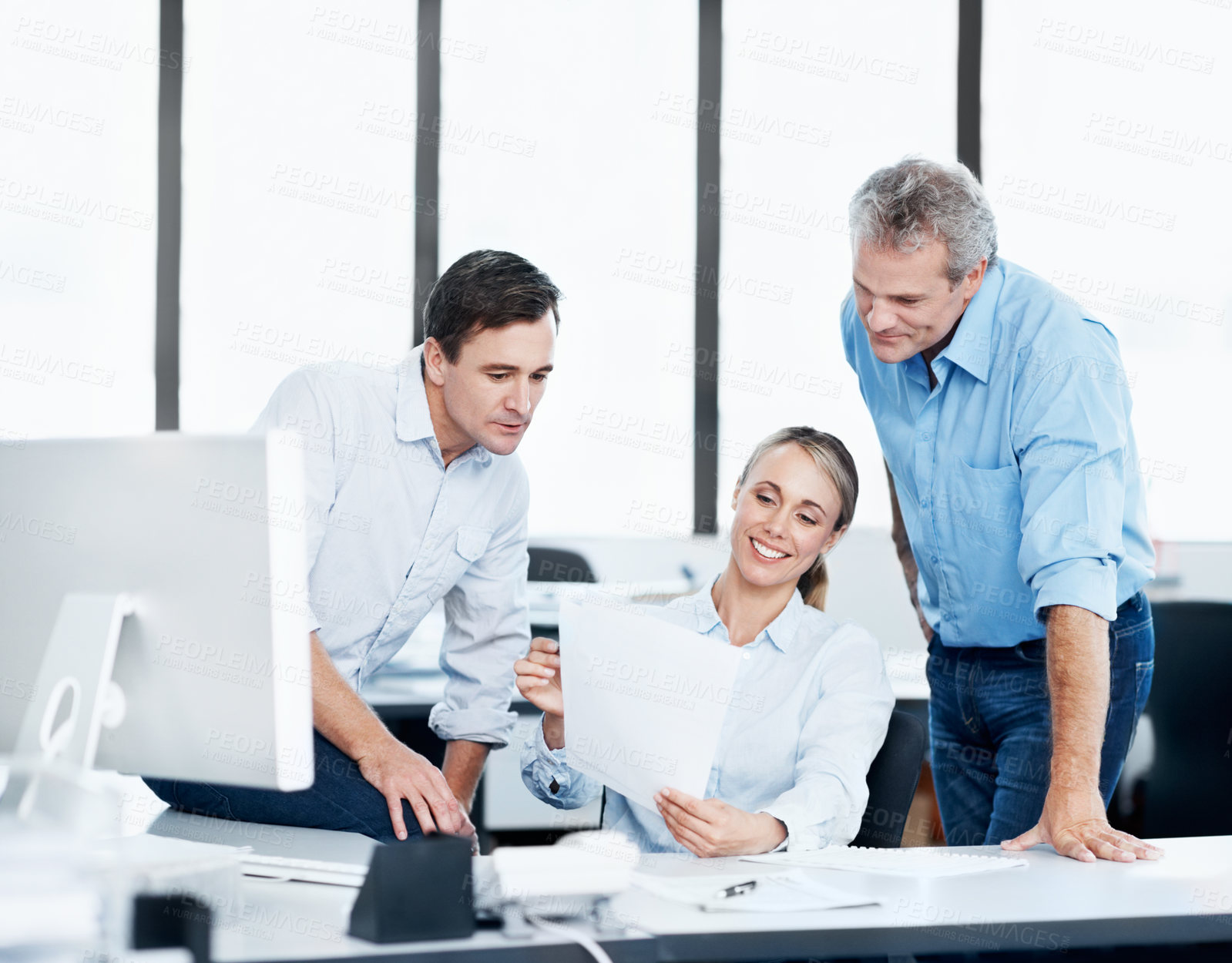 Buy stock photo Three coworkers looking over some paperwork in the office
