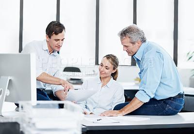 Buy stock photo Three colleagues looking over some paperwork in the office