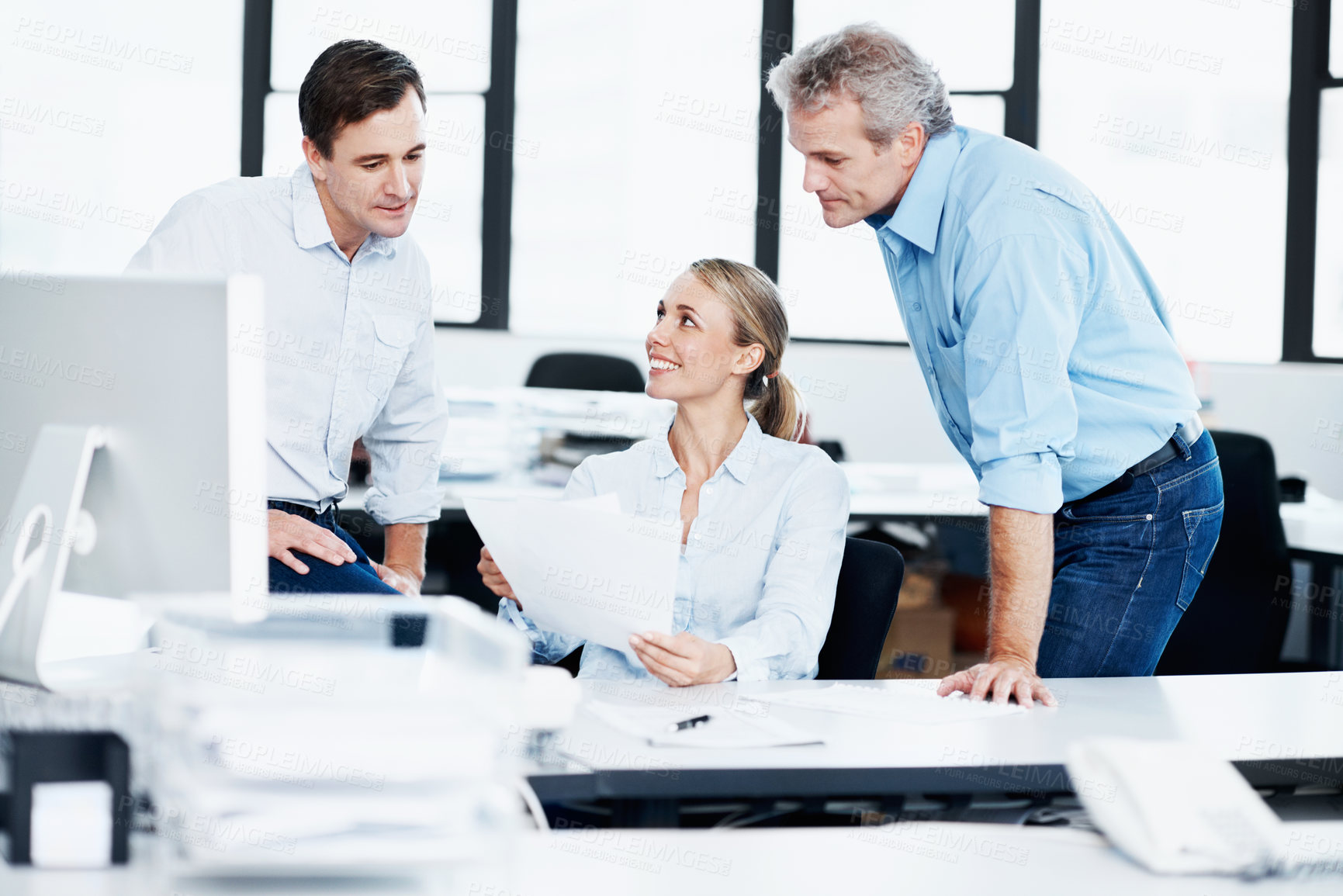Buy stock photo Three coworkers looking over some paperwork in the office