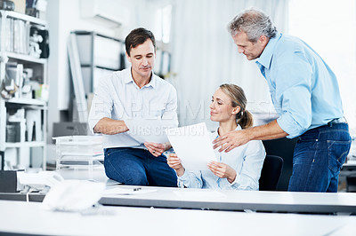 Buy stock photo Three businespeople looking over some documents in the office
