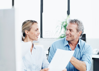 Buy stock photo Two colleagues looking over some paperwork in the office