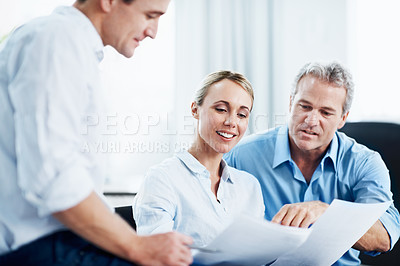 Buy stock photo Three colleagues having a discussion over some documents in the office