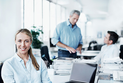 Buy stock photo Portrait of an attractive young businesswoman sitting at her desk with her coworkers in the background