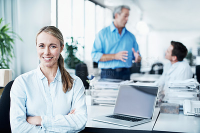 Buy stock photo Portrait of an attractive young businesswoman sitting at her desk with her colleagues in the background