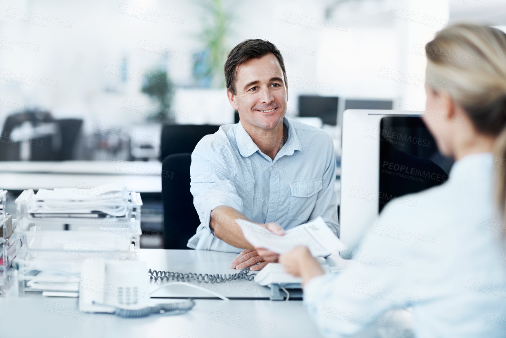 Buy stock photo A handsome young businessman handing his female coworker a document