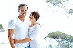 A mature couple in matching clothes embracing each other in a park