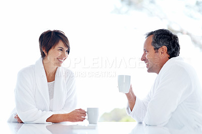 Buy stock photo Couple, conversation and happy with coffee at house for break, relax or morning start with drink. People, married and chat with beverage, smile and bonding for relationship and routine in home