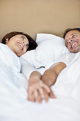 Buy stock photo Love, holding hands and smile with couple in bedroom in home for wake up, connection or romantic partner. Bonding, support and morning with mature man and woman in bed in apartment for trust and care