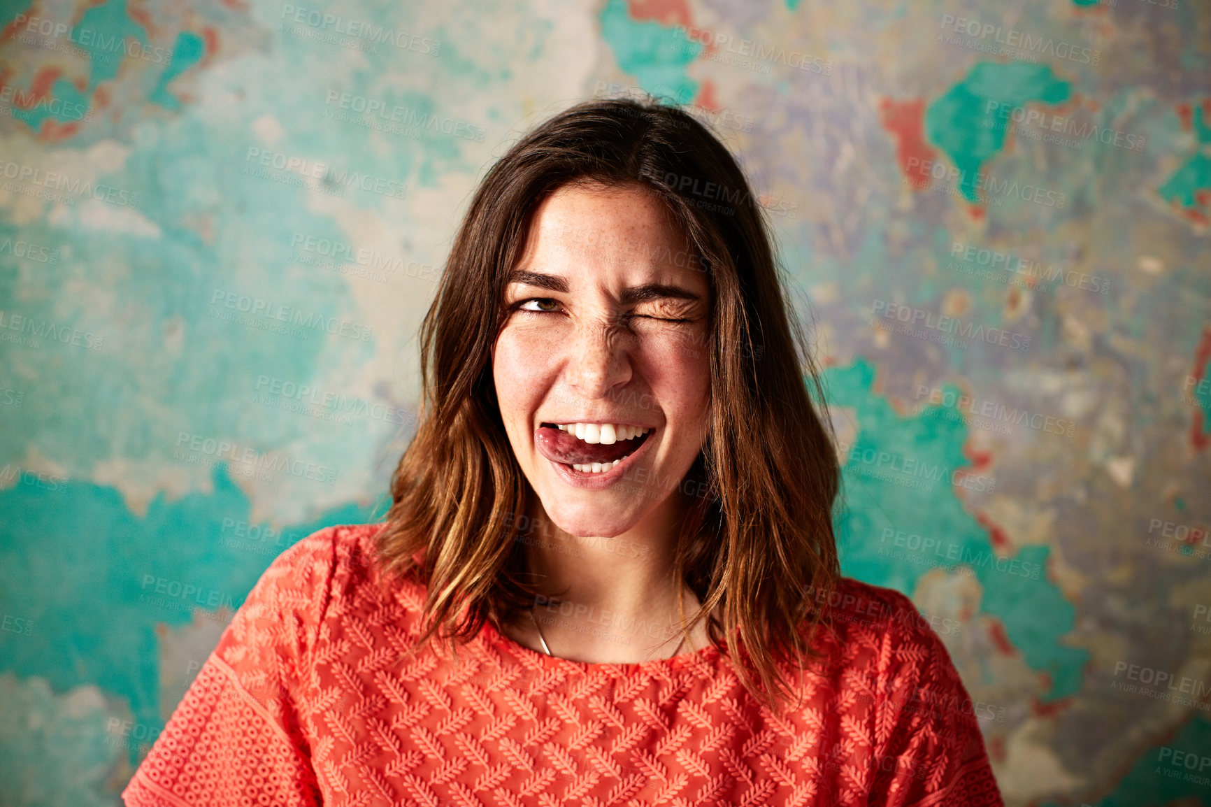 Buy stock photo Portrait of a young woman pulling a face in front of a colorful wall
