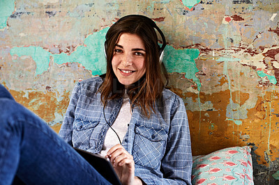 Buy stock photo Shot of a young woman using a digital tablet and headphones indoors