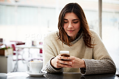 Buy stock photo Shot of a young woman using a mobile phone in a coffee shop