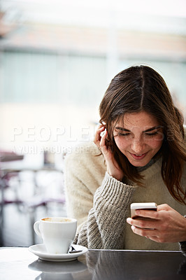 Buy stock photo Shot of a young woman using a mobile phone in a coffee shop