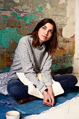Buy stock photo Shot of a young woman sitting on the floor in a thoughtful moment