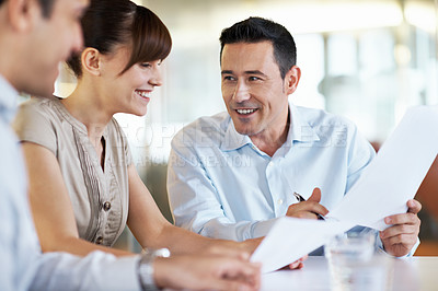 Buy stock photo Shot of coworkers discussing paperwork around a table in an office