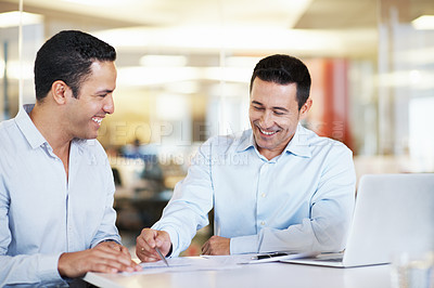 Buy stock photo Shot of two coworkers using a laptop at a table in an office