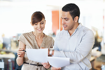 Buy stock photo Shot of two colleagues discussing paperwork while standing in an office