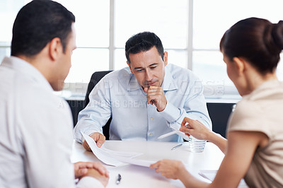 Buy stock photo Shot of coworkers discussing paperwork around a table in an office