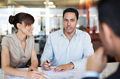 Buy stock photo Shot of coworkers discussing paperwork around a table in an office
