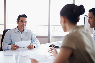 Buy stock photo Shot of coworkers discussing paperwork around a table in an office
