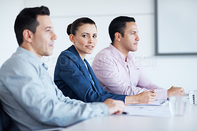 Buy stock photo Portrait of a young office worker sitting at a conference table between colleagues