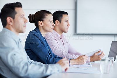 Buy stock photo Shot of a three coworkers siting in a row at a conference table