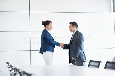 Buy stock photo Shot of two businesspeople shaking hands in a conference room