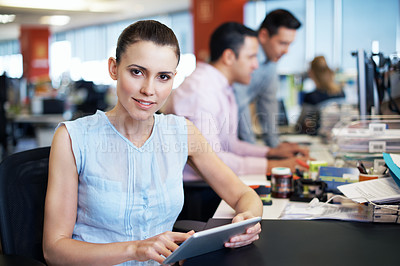 Buy stock photo Portrait of a young professional using a digital tablet while sitting at her desk in an office