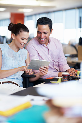 Buy stock photo Shot of two coworkers using a digital tablet while sitting at their desks in an office