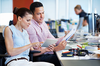 Buy stock photo Shot of two coworkers using a digital tablet while sitting at their desks in an office