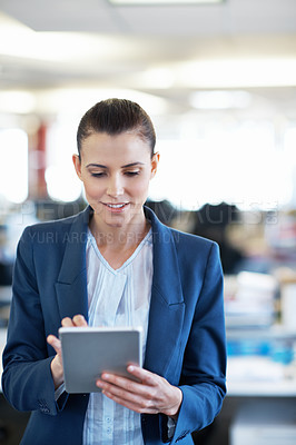 Buy stock photo Shot of a young woman using a digital tablet while standing in an office