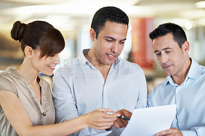 Buy stock photo Shot of three colleagues discussing paperwork in an office