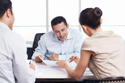Buy stock photo Shot of coworkers discussing paperwork around a table in an office