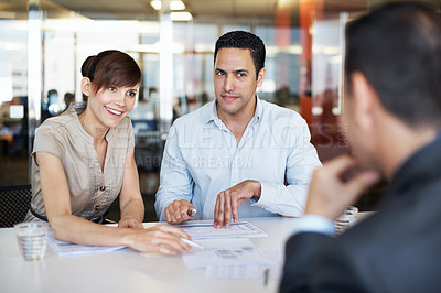 Buy stock photo Shot of coworkers discussing paperwork around a table in an office