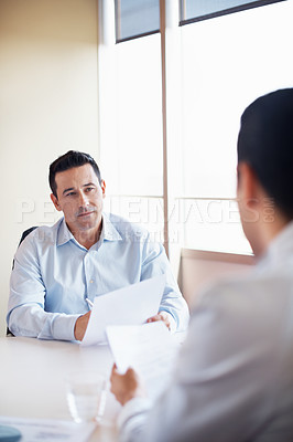 Buy stock photo Shot of two colleagues discussing paperwork around a table