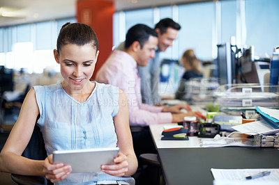 Buy stock photo Shot of a young professional using a digital tablet while sitting at her office desk