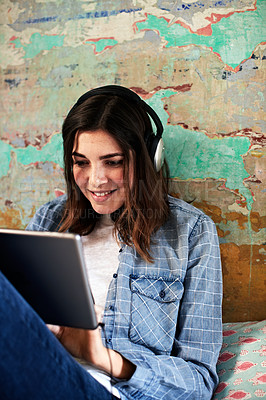 Buy stock photo Shot of a young woman using a digital tablet and headphones indoors