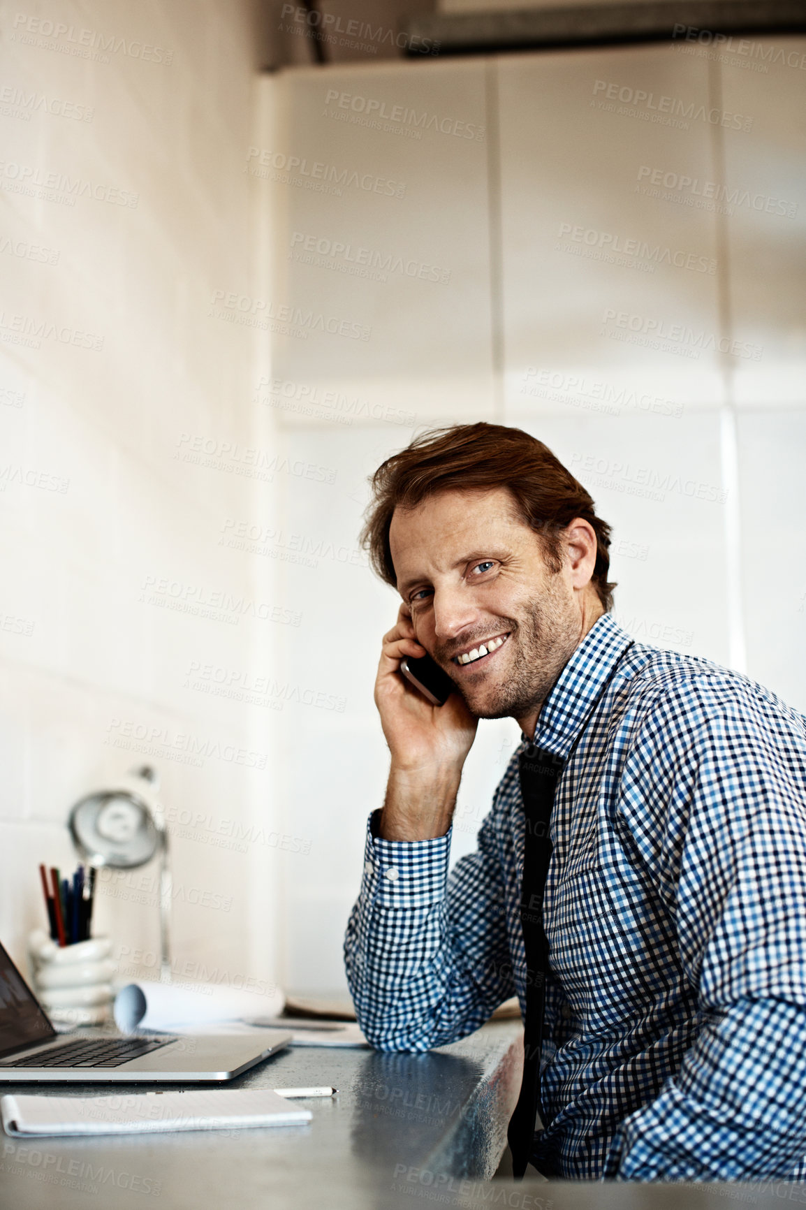Buy stock photo Shot of a businessman sitting at his desk talking on a cellphone