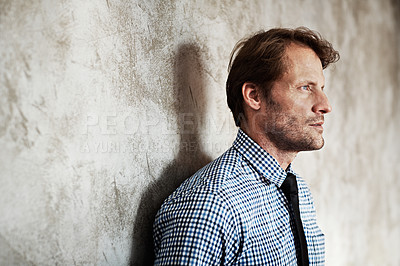 Buy stock photo Studio shot of a thoughtful looking businessman leaning against a wall