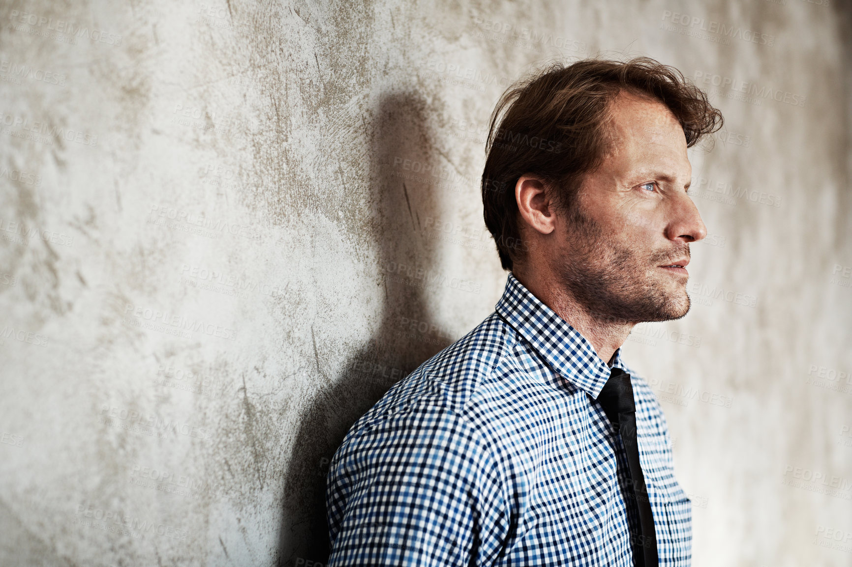 Buy stock photo Studio shot of a thoughtful looking businessman leaning against a wall