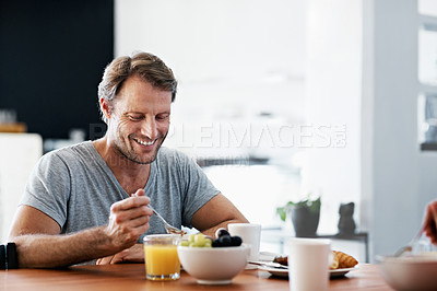 Buy stock photo Shot of a man eating breakfast at the dining table
