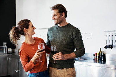 Buy stock photo Shot of a smiling mature couple drinking wine in their kitchen