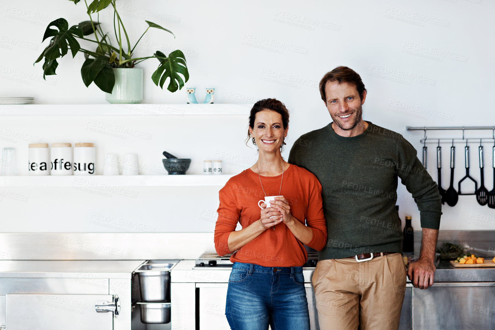 Buy stock photo Portrait of a smiling mature couple standing in their kitchen