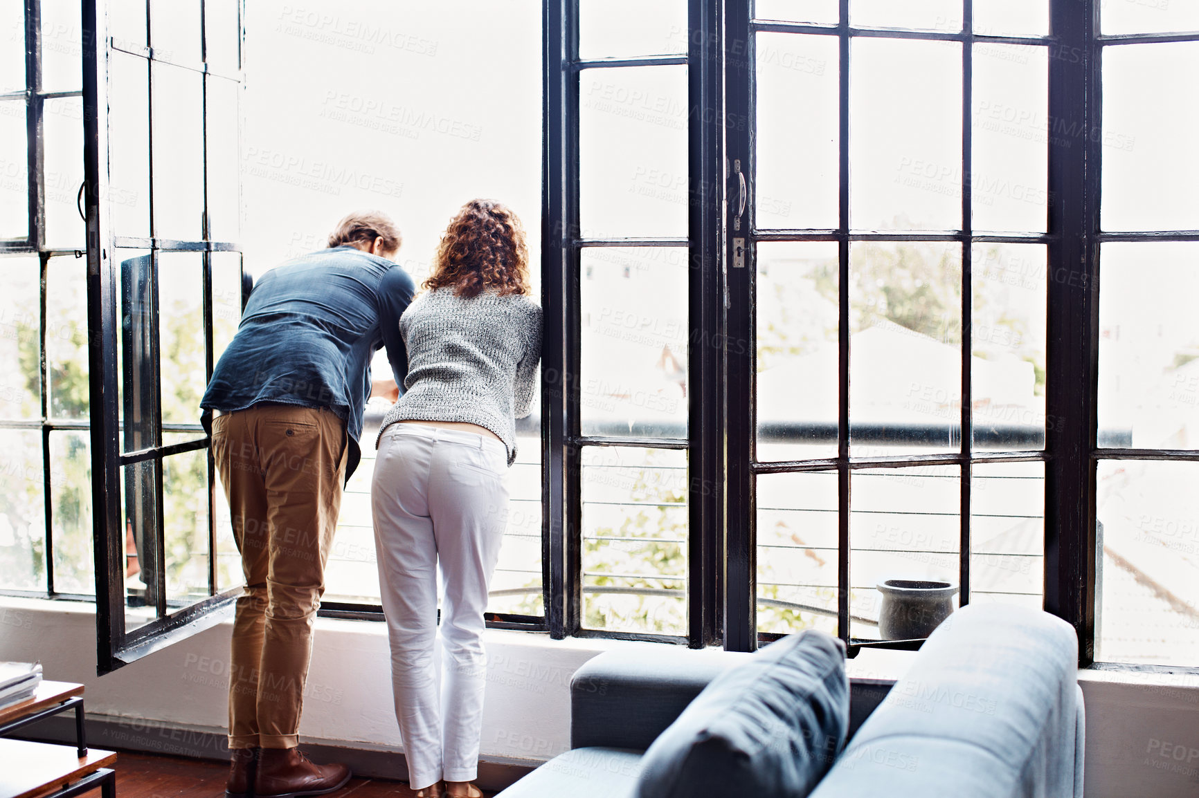 Buy stock photo Rearview shot of a mature couple leaning on their balcony railing looking outside