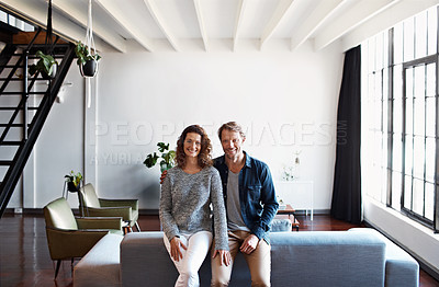 Buy stock photo Portrait of a smiling mature couple leaning on a sofa in their living room