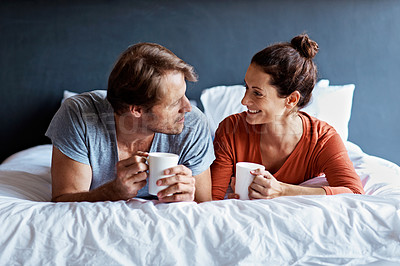 Buy stock photo Shot of a mature couple lying on their bed drinking coffee