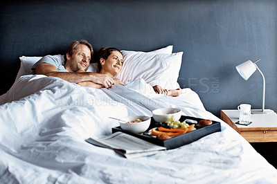 Buy stock photo Shot of a mature couple lying in bed with a breakfast tray beside them